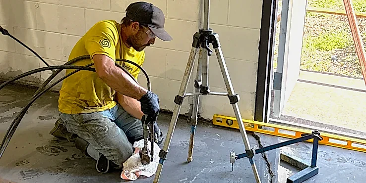 Foreman injecting polyurethane grout under a concrete slab in a commercial building.