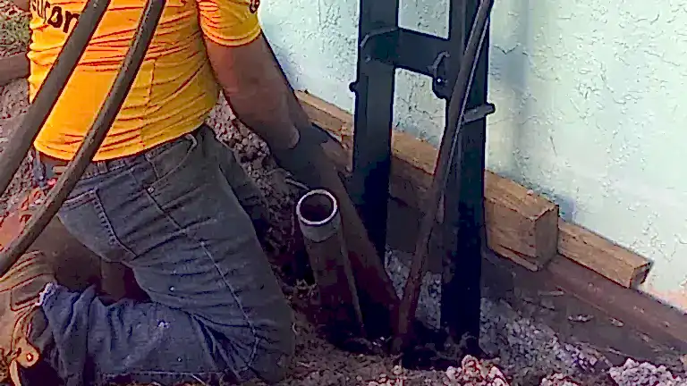 residential-crewinstallingpiers Technician installing a steel foundation pier beside an exposed home footing during foundation repair.