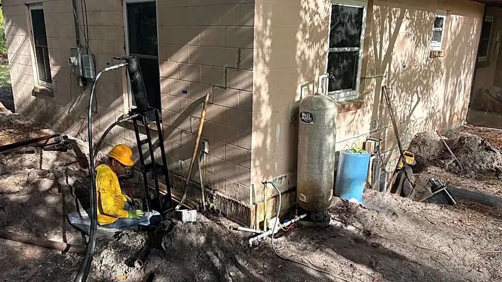 When Stair-Step Cracks Signal a Bigger Foundation Repair Problem in a Port Orange Home 2 Foundation repair work in progress with a technician operating hydraulic equipment beside an excavated wall.