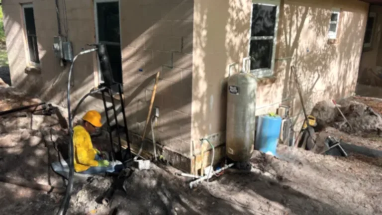 residential-underpinningfoundation Foundation repair work in progress with a technician operating hydraulic equipment beside an excavated wall.